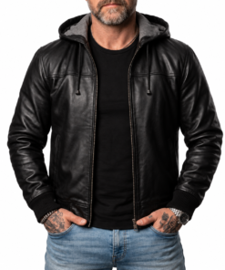 Front of a bearded man wearing the zipped Nintenzo black leather hooded bomber jacket with tattooed hands in pockets.